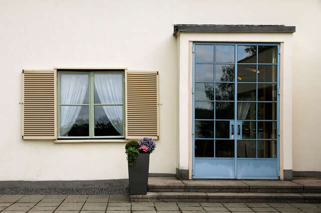 Door with light blue frames and a tall square window with window shutters.