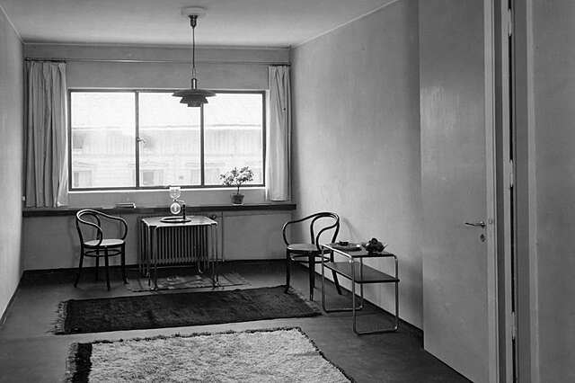 Black and white picture of and old room with two chais and side tables.