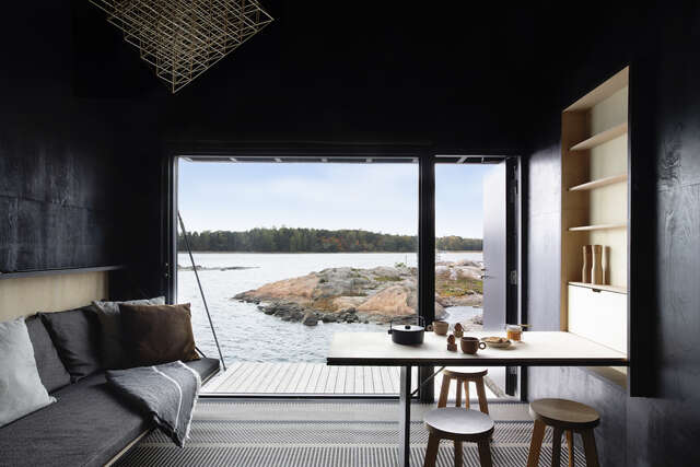 View from inside a black-tarnished wooden cabin towards rocky shoreline