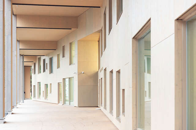 Outer wall of a large wooden building with multiple different sized windows.