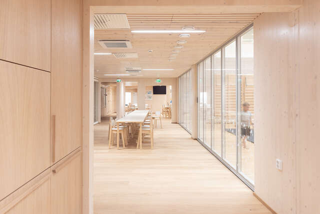 Room with wooden interior, large table in the middle and a glass wall to the right.