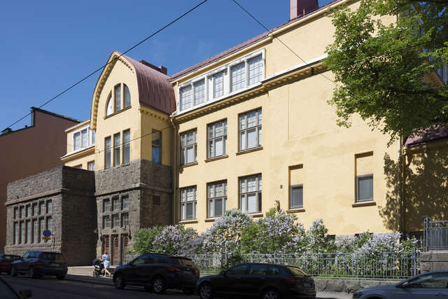 Yellow facade of a three storey building with a stone entrance.