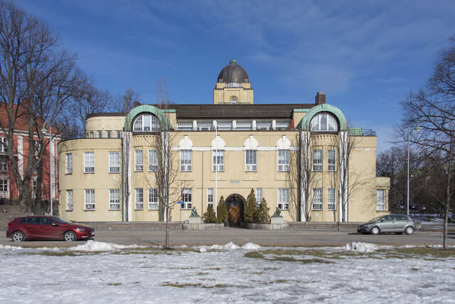 Yellow facade with white framed windows, arch details and a cupola.