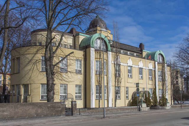 Yellow facade with white framed windows, arch details and a cupola.