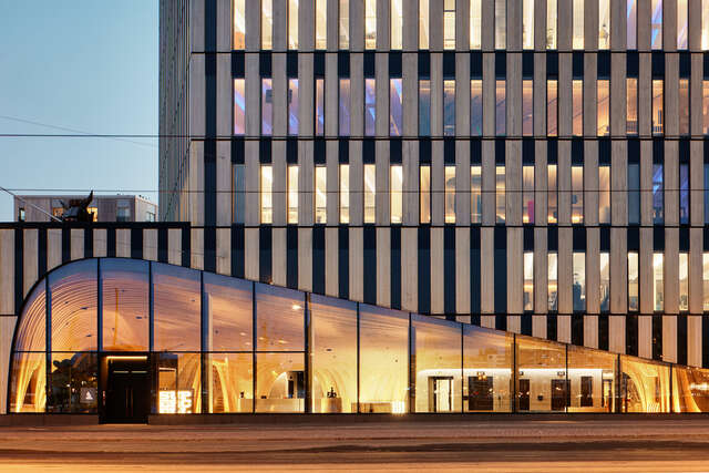 Building exterior on street level at night time. Lights on inside the building.