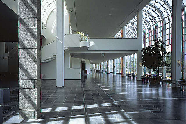 Large open space with white and stone structures and window walls letting in light.