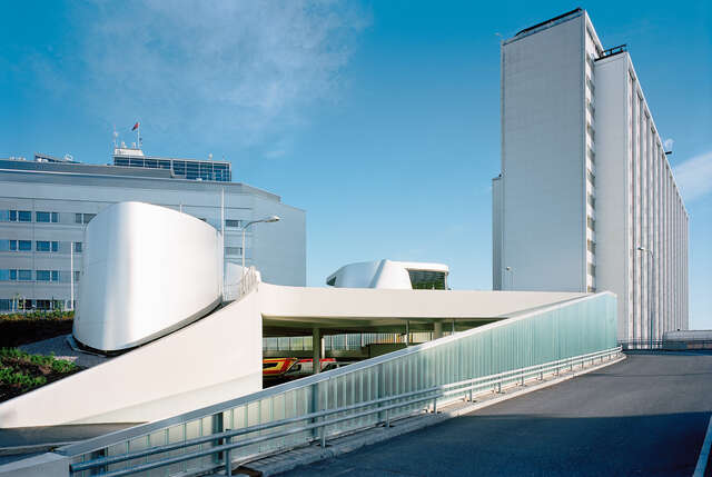 Driveway rising to a hospital tower next to rounded white elements