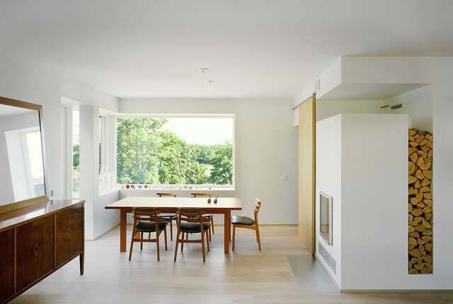 Spacious dining corner next to a corner window, the fireplace next to the dining table has built in storage for logs behind it.