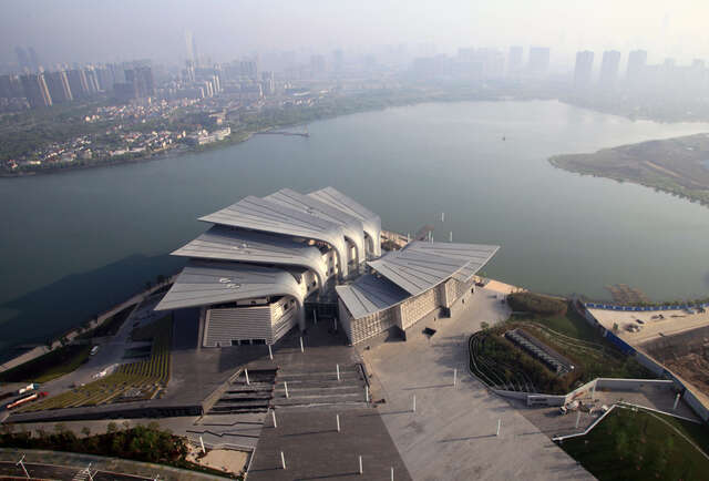 Sculptural building at a lake, high-rise city in the horizont