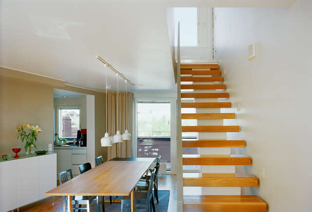 Interior with a dinette and wooden stairs, balcony in the back of the space