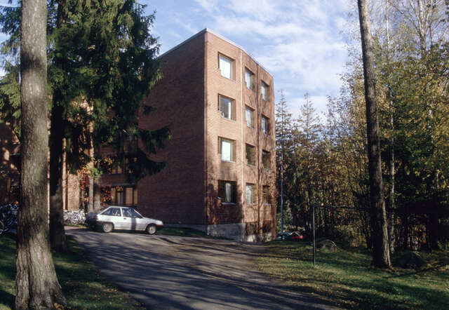 Paved road to the red-brick building with trees by the side