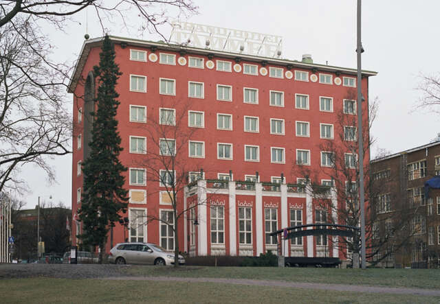 Red painted hotel building, a car in front of it.