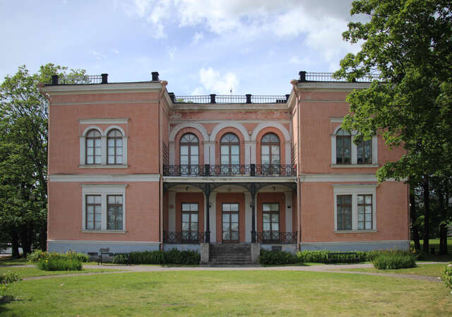 Terracotta coloured facade with grid windows and arch details.