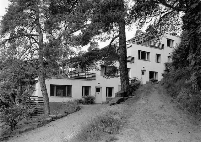 Stepped terrace house with a sand road and pines in the foreground