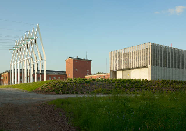 Powerlines next to a brick building and a square stone building.