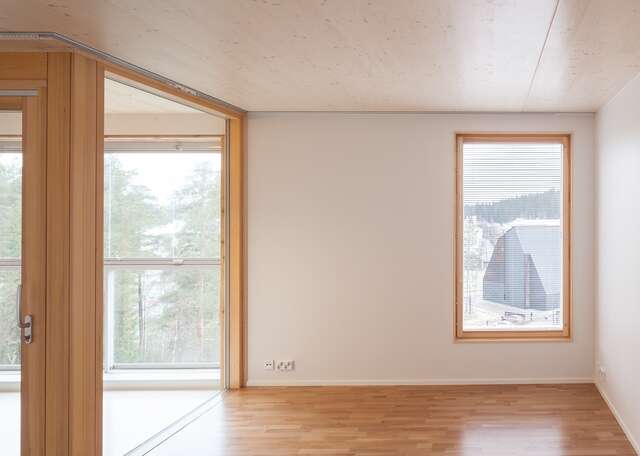 too with white walls, wooden floor, ceiling and window frame. The balcony is connected at the left and shares a glass wall with the room.