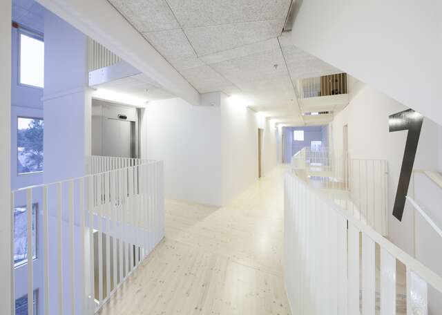 White hallway with white metal railing s on each sides and an elevator to the left.