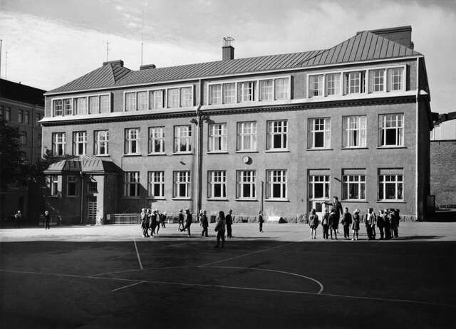 Children playing in the playground in front of the schools back facade.
