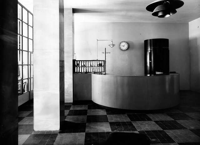 Hotel reception with a black and white checkered floor and simple sleek furniture.