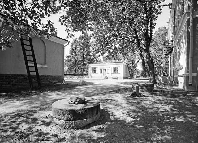 Black and white picture of a well and some buildings surrounding it.