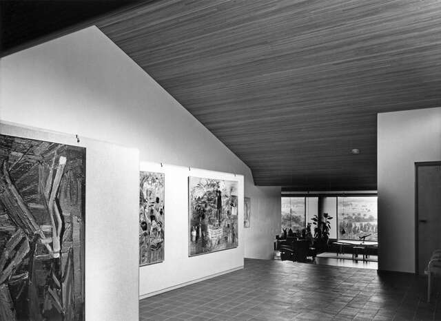 Foyer with paintings on the wall and a descending wooden ceiling looking towards the garden