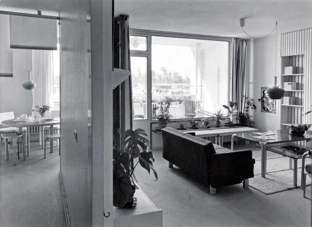 Dividing wall leaving a dining table on the left, and a living room with sitting area and access to the balcony on the right