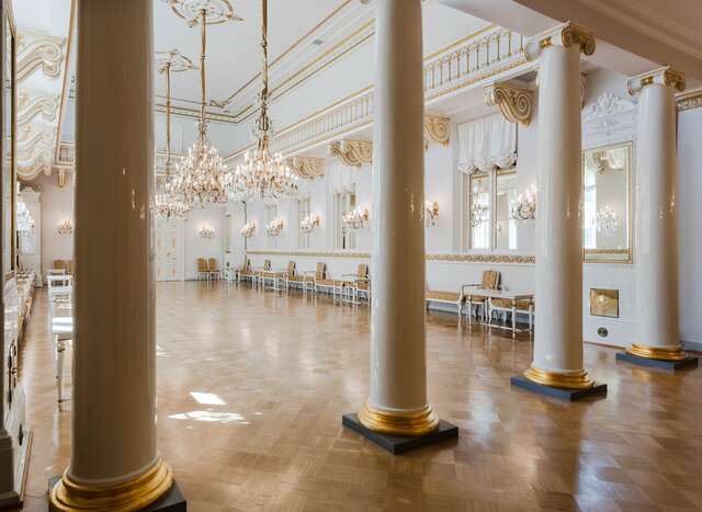 Large hall with white and gold decorative elements and chandeliers.