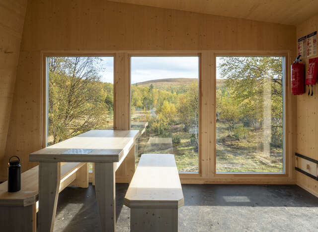 A bench inside a small hut with windows looking out