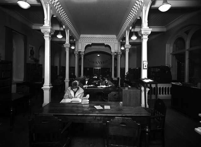 Dark reading room with decorative columns illuminated bu sunlight.