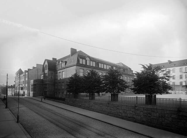 Black and white picture of the street with tram tracks and the school.