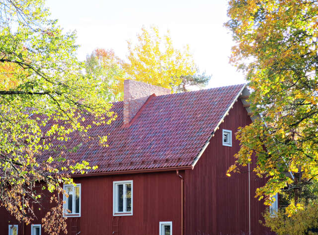 A building's roof made of different shades of tiles with a brick chimney.