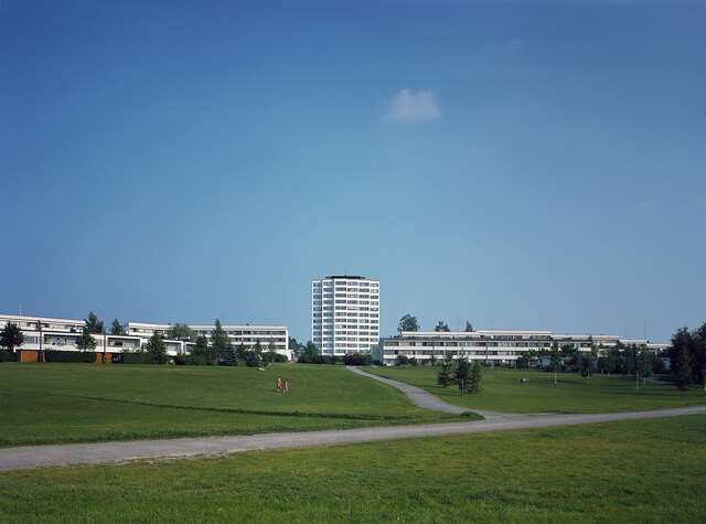 High-rise-block in the back, surrounded by lawn and the neighbourhood