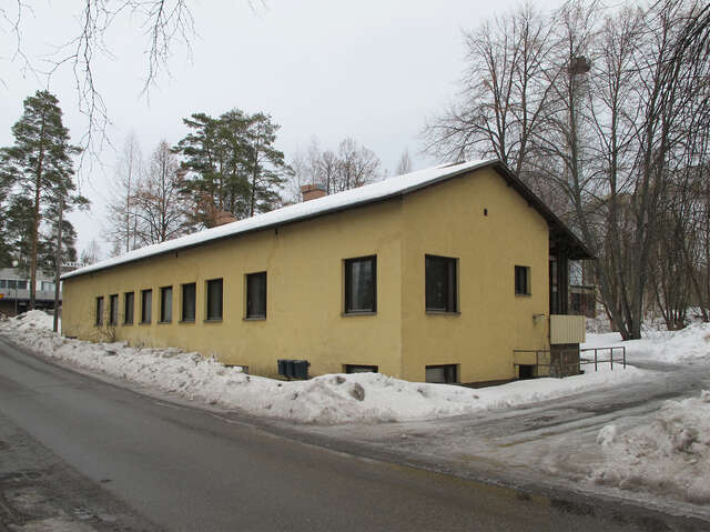 Long yellow plastered house with brown window frames on a grey winter day.