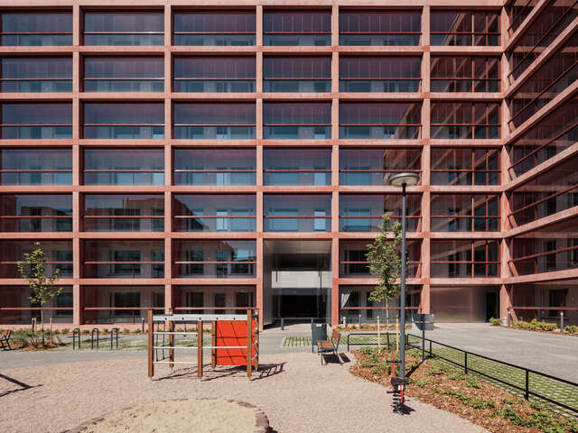 A playground in the courtyard of a large, red apartment building.