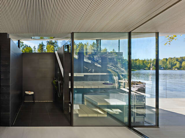 Shower area with black tiles and a sauna with glass windows that provides a view of the lake