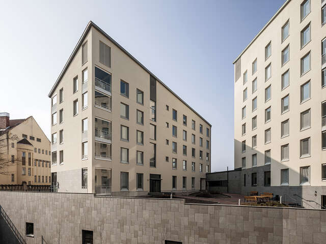 Beige plastered modern apartment buildings that are interconnected and share a courtyard.