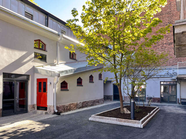 Inner courtyard with a tree in the centre. White old building with red door.