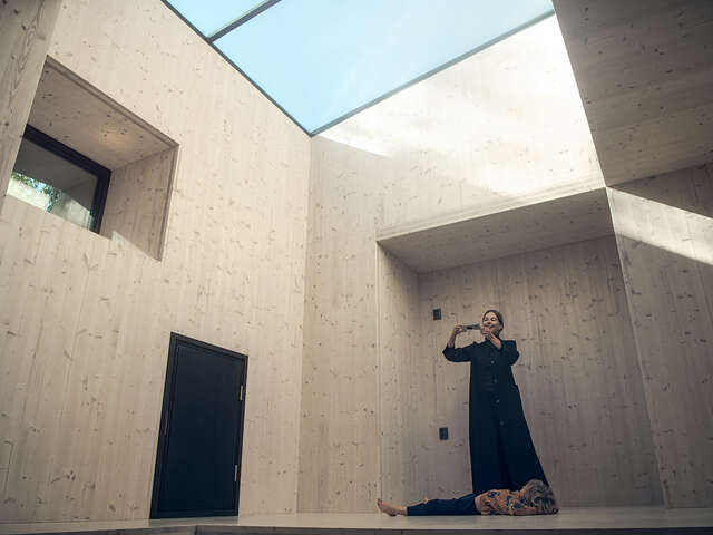 Interior of wooden structure with skylight above. One adult and child in room.