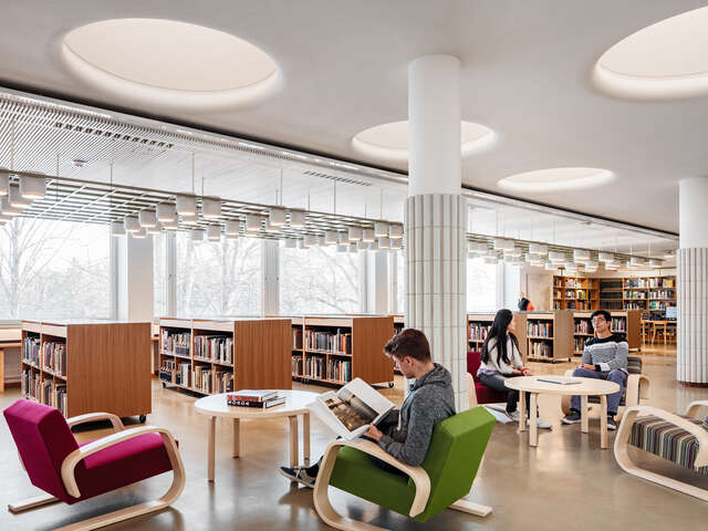 Library with a sitting area, the large windows show a snowy landscape.
