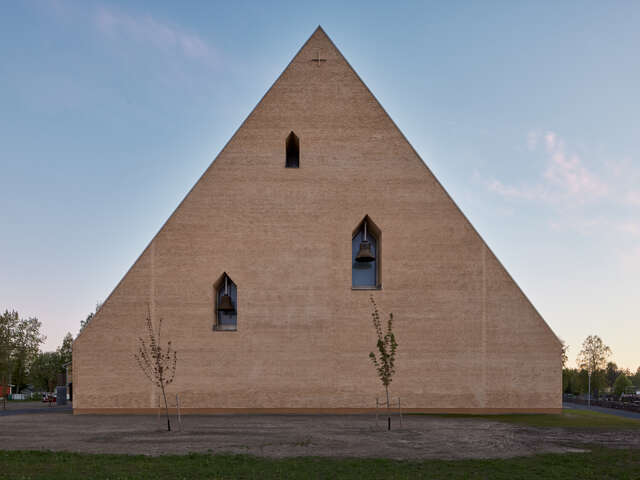 Wooden, triangle-shaped facade with three indentations in it. In each of the indentation, there is a church bell.