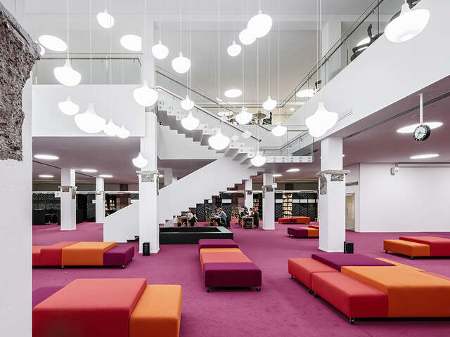 Sitting area with pink and orange carpet and furniture in an otherwise white environment.