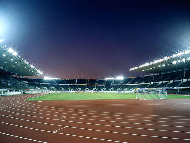Running track, lawn and auditorium with stadium lights in the background
