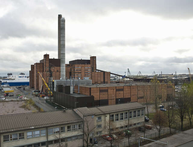 Red-colored power plant behind low industrial buildings