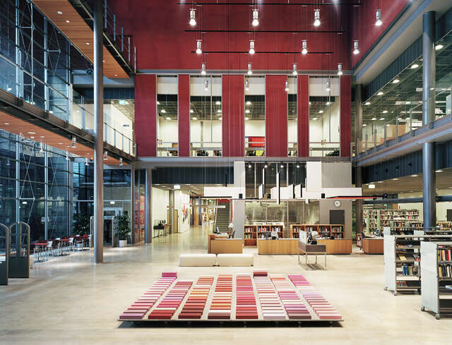 Entrance hall with red and purple decorative elements and otherwise stone, glass, wood and metal materials.