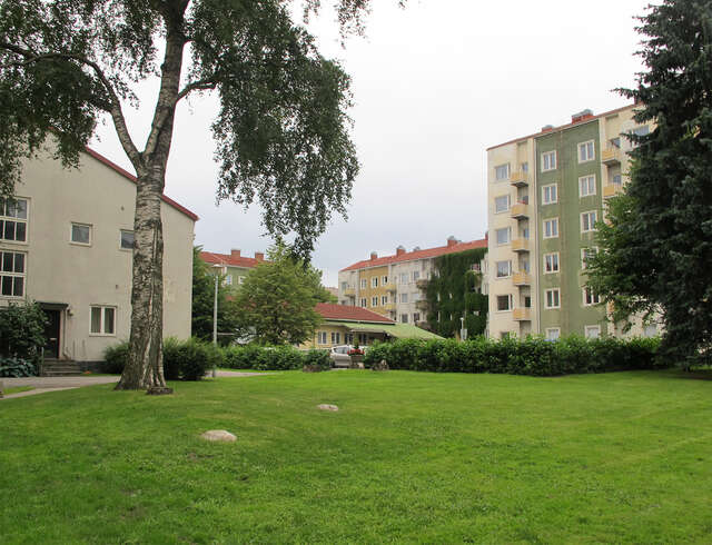 Lawn surrounded bu apartment buildings.