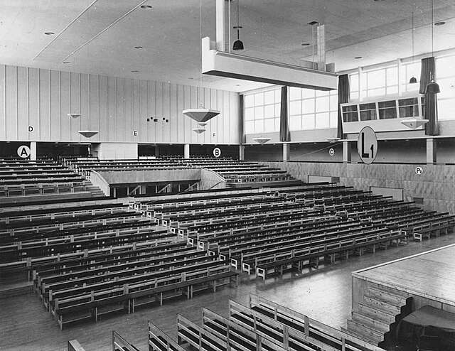 Interior of the Sports hall filled with wooden benches.
