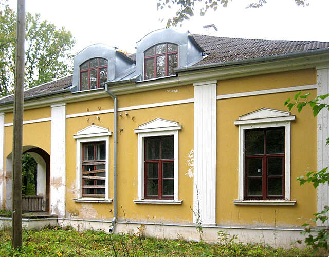 Old yellow house with white decorative elements and grid windows, the paint has chipped in several points.