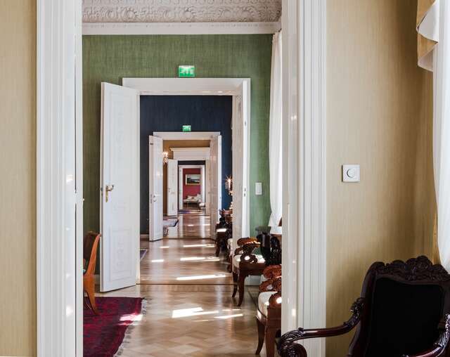hallway of open white ornate doors through different colored rooms.