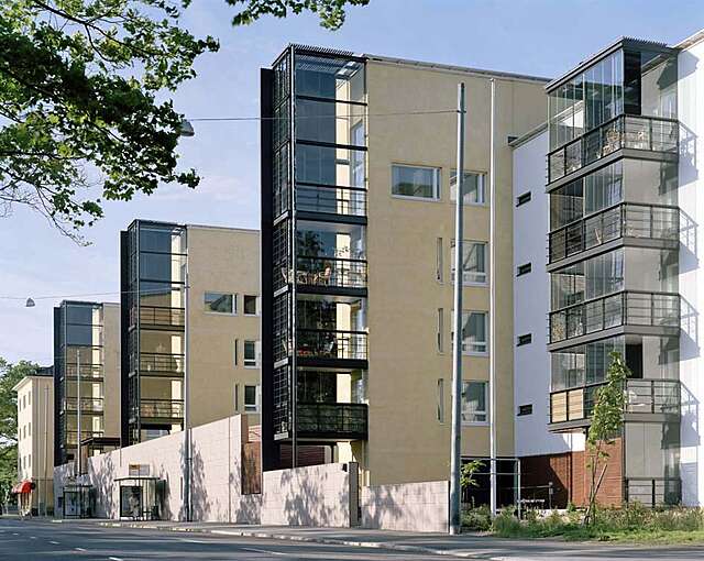 Apartment building complex with three buildings with plaster, glass and metal elements.