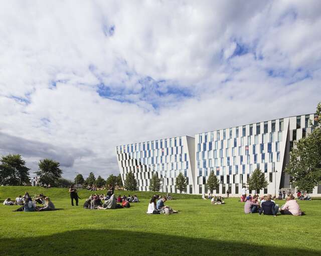 People sitting on a lawn in front of the office building.